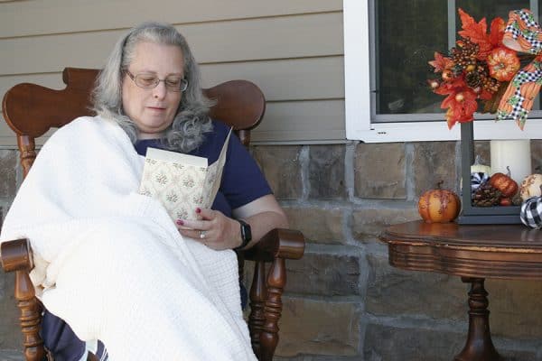 A woman reading a book on a porch.