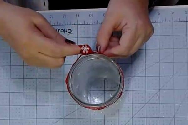 Tieing a bow in a ribbon around the rim of a mason jar - alifeofbalance.com