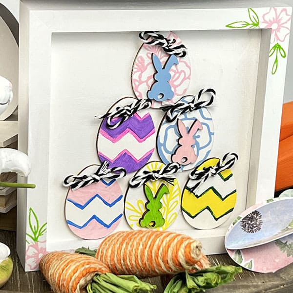Wooden sign with Easter egg cutouts on an Easter tieried tray