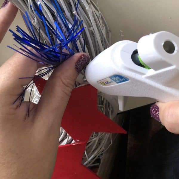 Gluing sparklers to a grapevine wreath above wooden stars