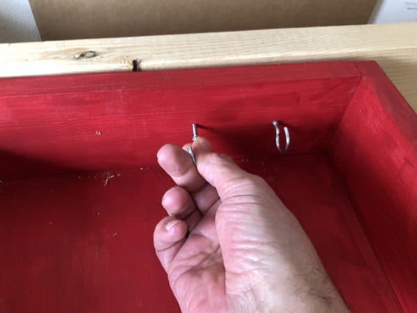 Hand inseerting cup hooks into grill tools organizer