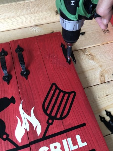 Drill attaching hinges to wooden doors for grill tools organizer