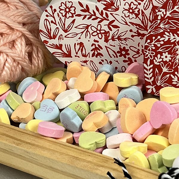 Candy Valentines hearts being used for a base when styling a tiered tray.